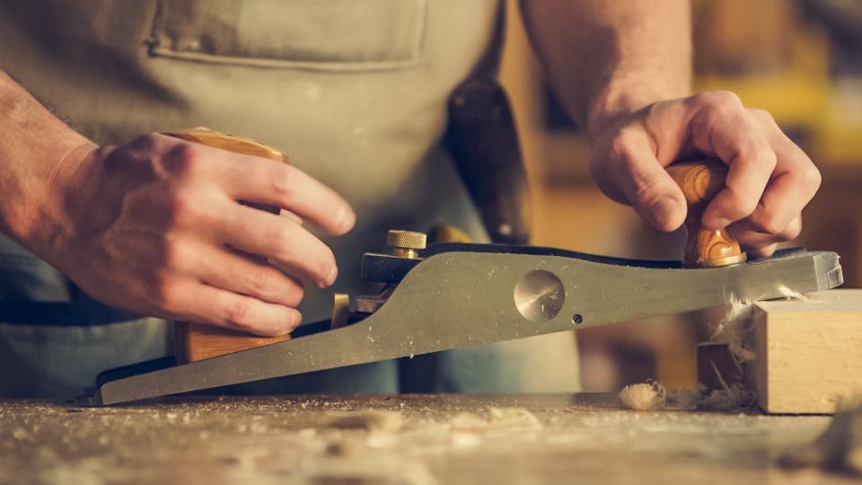 Hände an einem Hobel in der Werkstatt